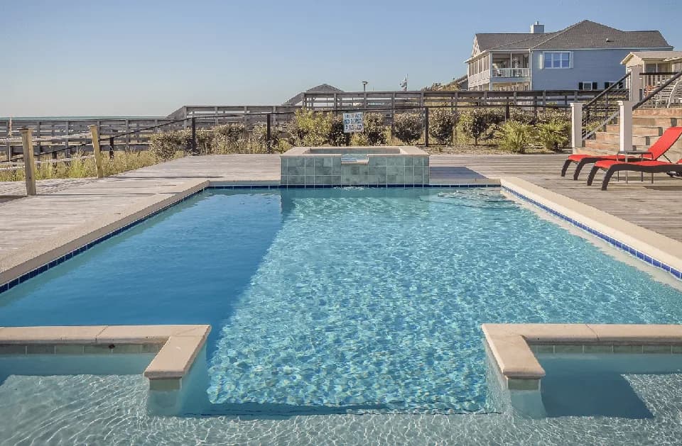 Rectangular pool with a raised spa and wide deck under a clear sky